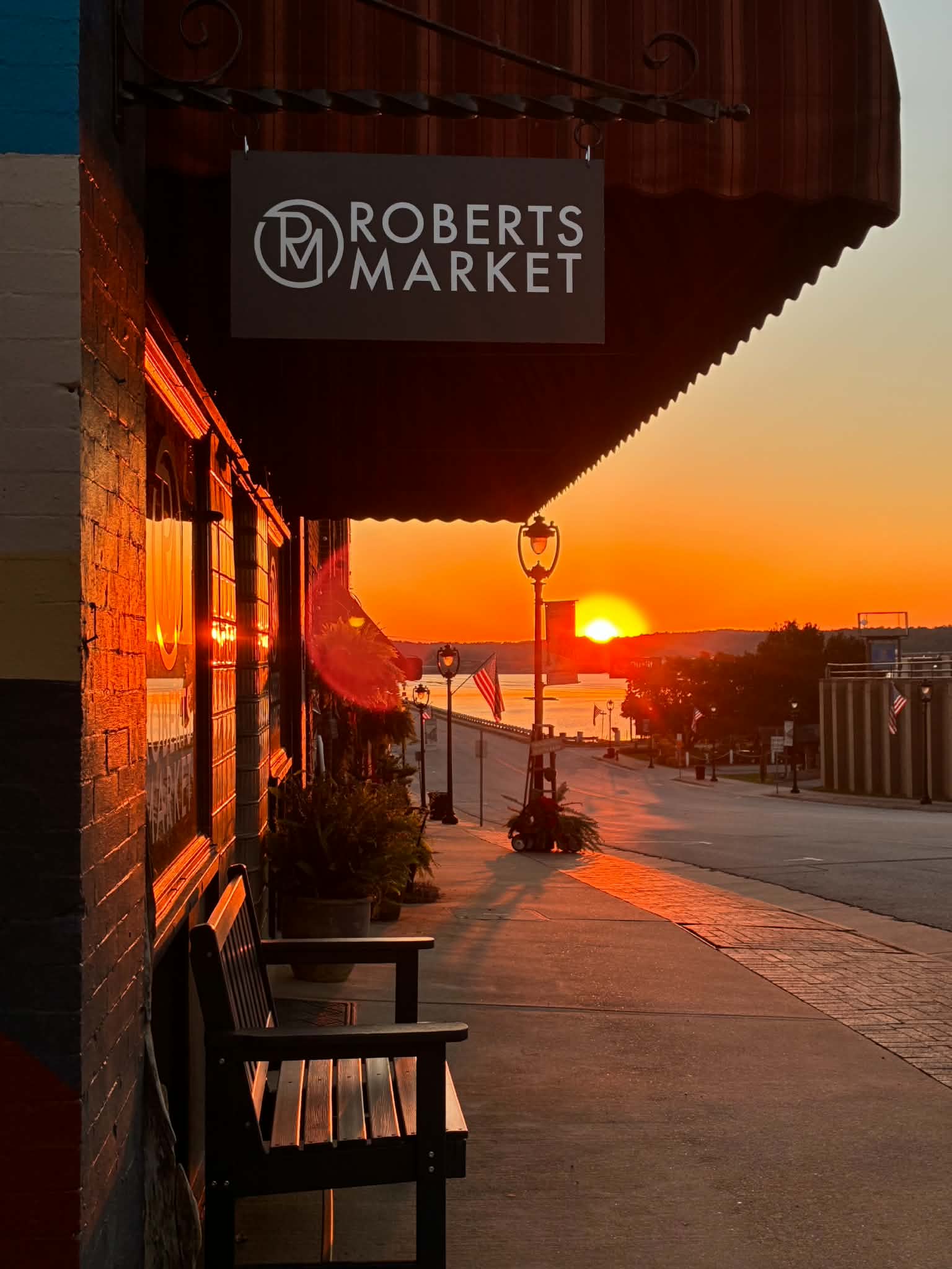 Roberts Market hanging sign at golden hour as the sun rises over the lake at the foot of Virginia Avenue in Clarksville